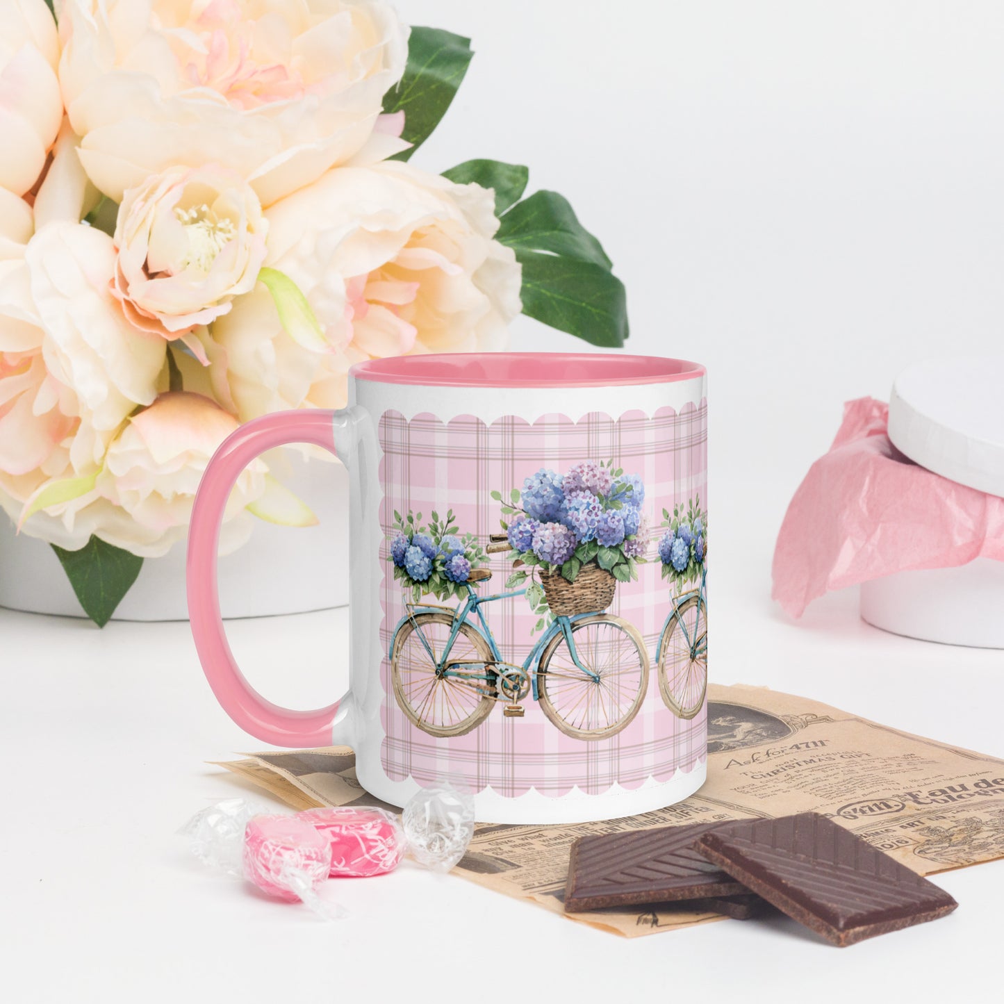White Mug with bicycle and flower design on a table with flowers and chocolate Pink interior and handle
